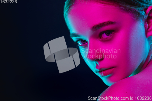 Image of Portrait of female fashion model in neon light on dark studio background.