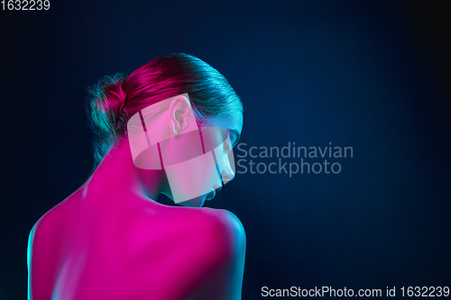 Image of Portrait of female fashion model in neon light on dark studio background.