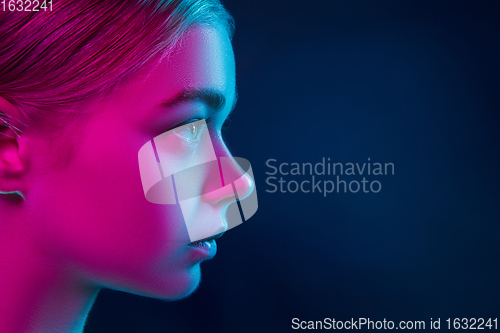 Image of Portrait of female fashion model in neon light on dark studio background.