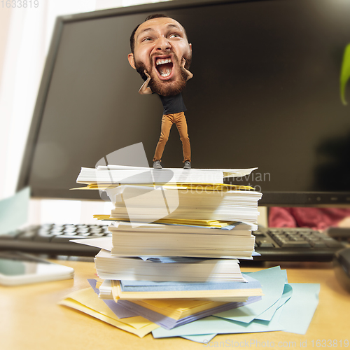 Image of Tired man, office worker holding his huge tired head, funny