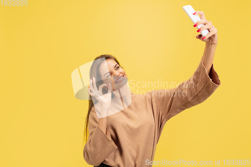 Image of Portrait of young caucasian woman with bright emotions isolated on yellow studio background