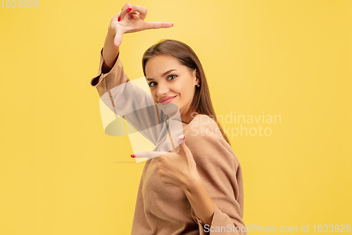 Image of Portrait of young caucasian woman with bright emotions isolated on yellow studio background