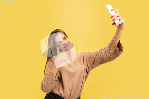 Image of Portrait of young caucasian woman with bright emotions isolated on yellow studio background