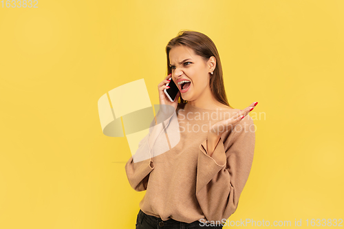 Image of Portrait of young caucasian woman with bright emotions isolated on yellow studio background