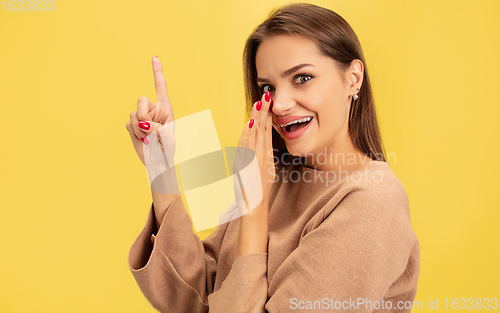 Image of Portrait of young caucasian woman with bright emotions isolated on yellow studio background