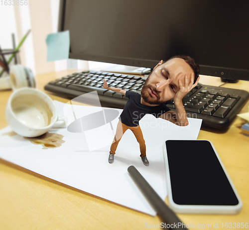 Image of Tired man, office worker holding his huge tired head, funny