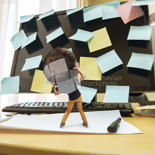 Image of Tired man, office worker holding his huge tired head, funny