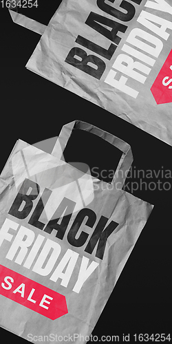 Image of Shopping bags with lettering black friday, sales concept. Flyer with copyspace. Dark neoned background