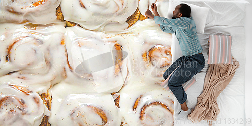 Image of Portrait of a young man sleeping and dreaming about buns and cookie