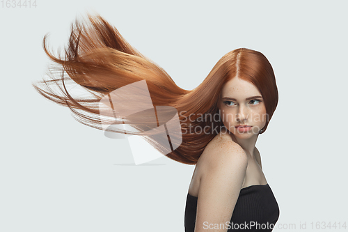 Image of Beautiful model with long smooth, flying red hair isolated on white studio background.