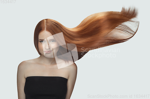 Image of Beautiful model with long smooth, flying red hair isolated on white studio background.