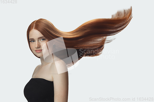 Image of Beautiful model with long smooth, flying red hair isolated on white studio background.