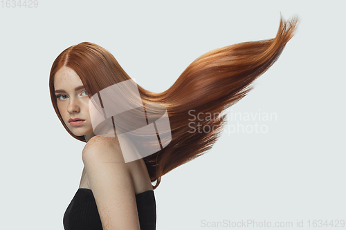 Image of Beautiful model with long smooth, flying red hair isolated on white studio background.