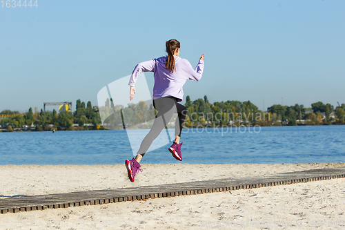 Image of Young woman training outdoors in autumn sunshine. Concept of sport, healthy lifestyle, movement, activity.