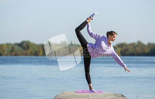 Image of Young woman training outdoors in autumn sunshine. Concept of sport, healthy lifestyle, movement, activity.