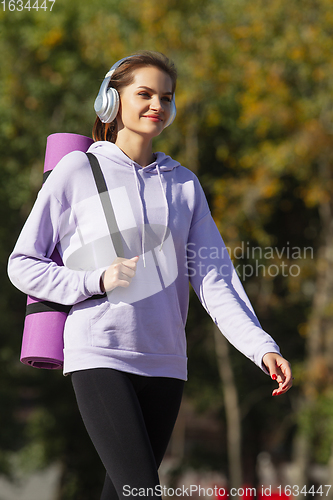 Image of Young woman training outdoors in autumn sunshine. Concept of sport, healthy lifestyle, movement, activity.