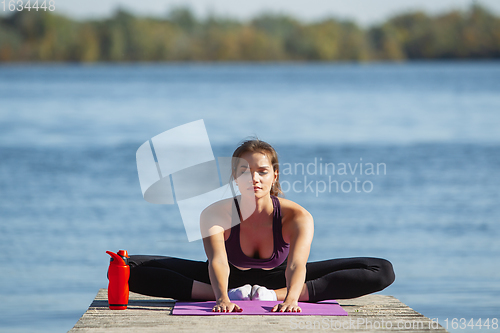 Image of Young woman training outdoors in autumn sunshine. Concept of sport, healthy lifestyle, movement, activity.