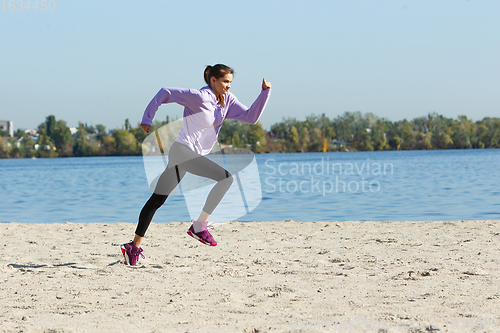 Image of Young woman training outdoors in autumn sunshine. Concept of sport, healthy lifestyle, movement, activity.