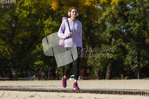 Image of Young woman training outdoors in autumn sunshine. Concept of sport, healthy lifestyle, movement, activity.