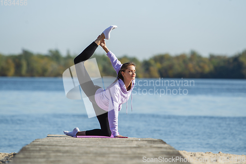 Image of Young woman training outdoors in autumn sunshine. Concept of sport, healthy lifestyle, movement, activity.