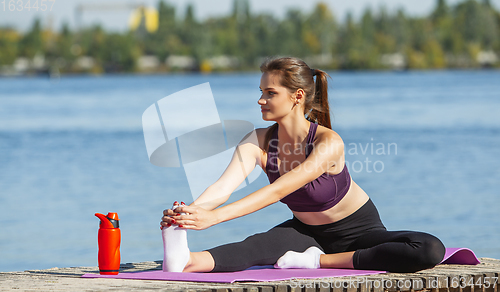 Image of Young woman training outdoors in autumn sunshine. Concept of sport, healthy lifestyle, movement, activity.