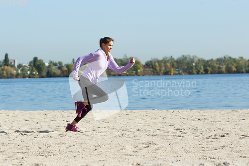 Image of Young woman training outdoors in autumn sunshine. Concept of sport, healthy lifestyle, movement, activity.