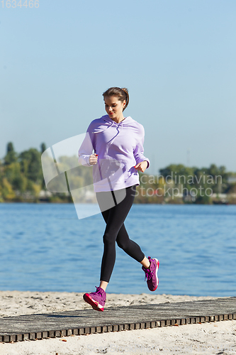 Image of Young woman training outdoors in autumn sunshine. Concept of sport, healthy lifestyle, movement, activity.