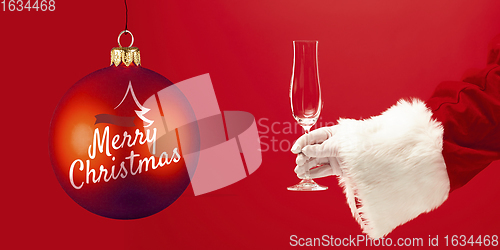 Image of Hand of Santa Claus holding glass, greeting with New Year 2021 and Christmas. Flyer with copyspace