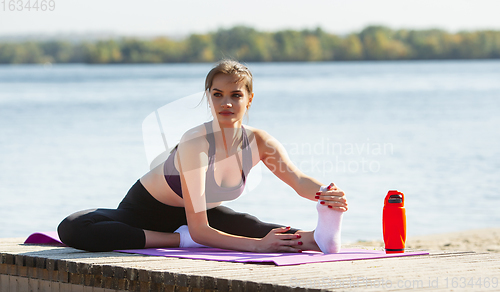 Image of Young woman training outdoors in autumn sunshine. Concept of sport, healthy lifestyle, movement, activity.