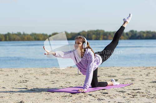 Image of Young woman training outdoors in autumn sunshine. Concept of sport, healthy lifestyle, movement, activity.