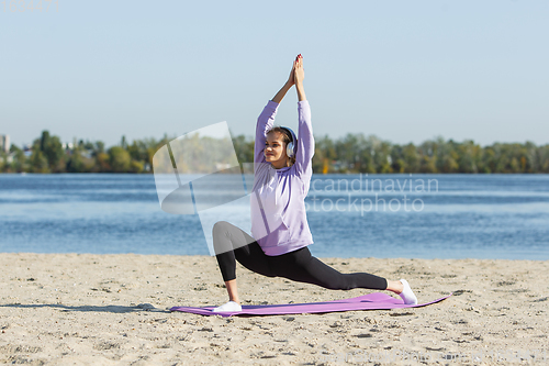 Image of Young woman training outdoors in autumn sunshine. Concept of sport, healthy lifestyle, movement, activity.