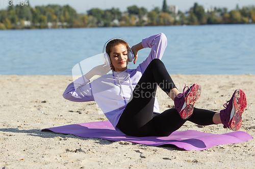 Image of Young woman training outdoors in autumn sunshine. Concept of sport, healthy lifestyle, movement, activity.