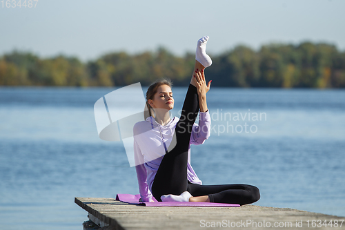 Image of Young woman training outdoors in autumn sunshine. Concept of sport, healthy lifestyle, movement, activity.