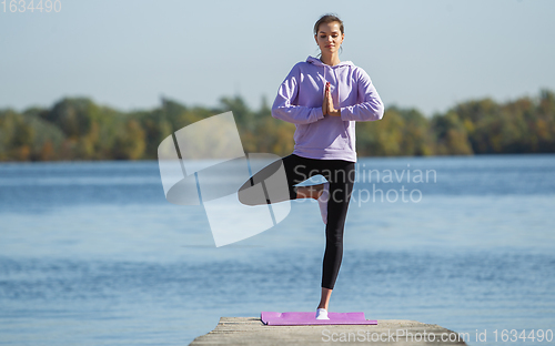 Image of Young woman training outdoors in autumn sunshine. Concept of sport, healthy lifestyle, movement, activity.