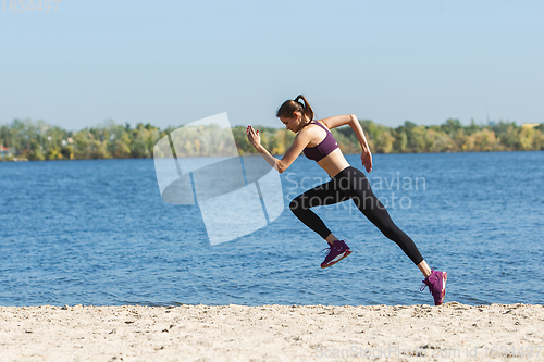 Image of Young woman training outdoors in autumn sunshine. Concept of sport, healthy lifestyle, movement, activity.