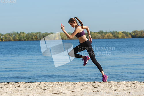 Image of Young woman training outdoors in autumn sunshine. Concept of sport, healthy lifestyle, movement, activity.