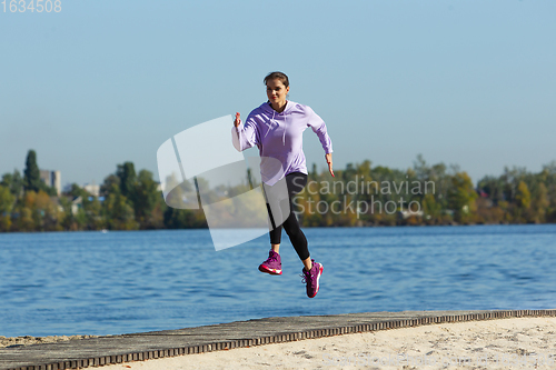 Image of Young woman training outdoors in autumn sunshine. Concept of sport, healthy lifestyle, movement, activity.