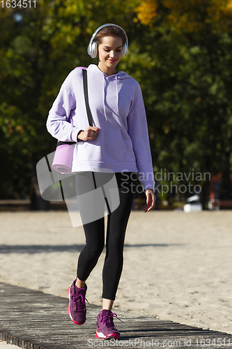 Image of Young woman training outdoors in autumn sunshine. Concept of sport, healthy lifestyle, movement, activity.