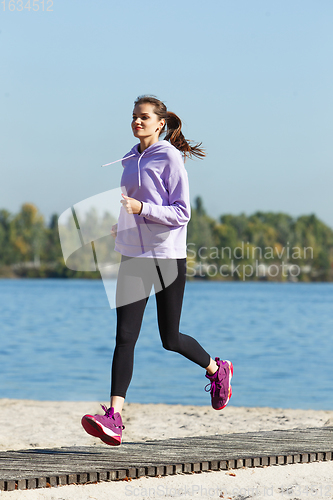 Image of Young woman training outdoors in autumn sunshine. Concept of sport, healthy lifestyle, movement, activity.