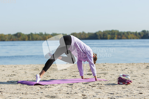 Image of Young woman training outdoors in autumn sunshine. Concept of sport, healthy lifestyle, movement, activity.