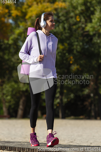 Image of Young woman training outdoors in autumn sunshine. Concept of sport, healthy lifestyle, movement, activity.