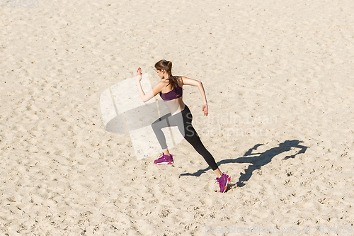 Image of Young woman training outdoors in autumn sunshine. Concept of sport, healthy lifestyle, movement, activity.