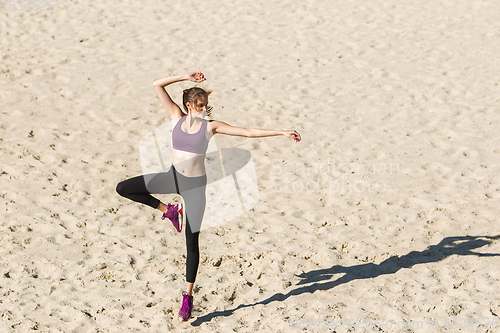 Image of Young woman training outdoors in autumn sunshine. Concept of sport, healthy lifestyle, movement, activity.