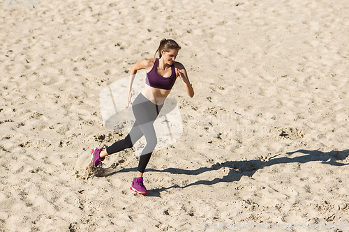 Image of Young woman training outdoors in autumn sunshine. Concept of sport, healthy lifestyle, movement, activity.