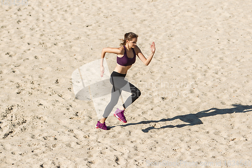 Image of Young woman training outdoors in autumn sunshine. Concept of sport, healthy lifestyle, movement, activity.