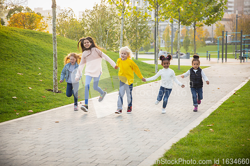 Image of Interracial group of kids, girls and boys playing together at the park in summer day