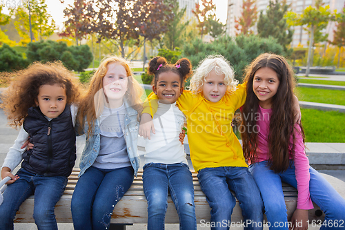 Image of Interracial group of kids, girls and boys playing together at the park in summer day