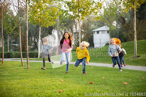 Image of Interracial group of kids, girls and boys playing together at the park in summer day