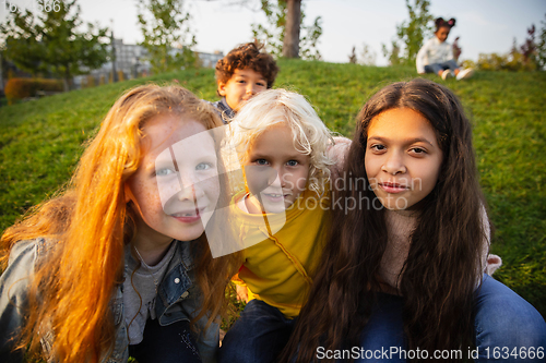 Image of Interracial group of kids, girls and boys playing together at the park in summer day