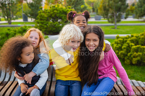 Image of Interracial group of kids, girls and boys playing together at the park in summer day